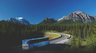 A bus driving through the mountains around Calgary taking people on a tour