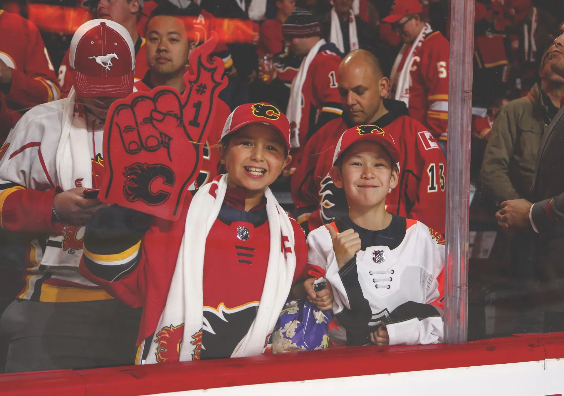 Family cheering near the glass at the Calgary Flames game at the Scotiabank Saddledome 