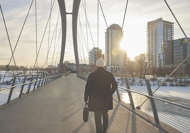 man walking across George C King bridge in East Village along Calgary's RiverWalk