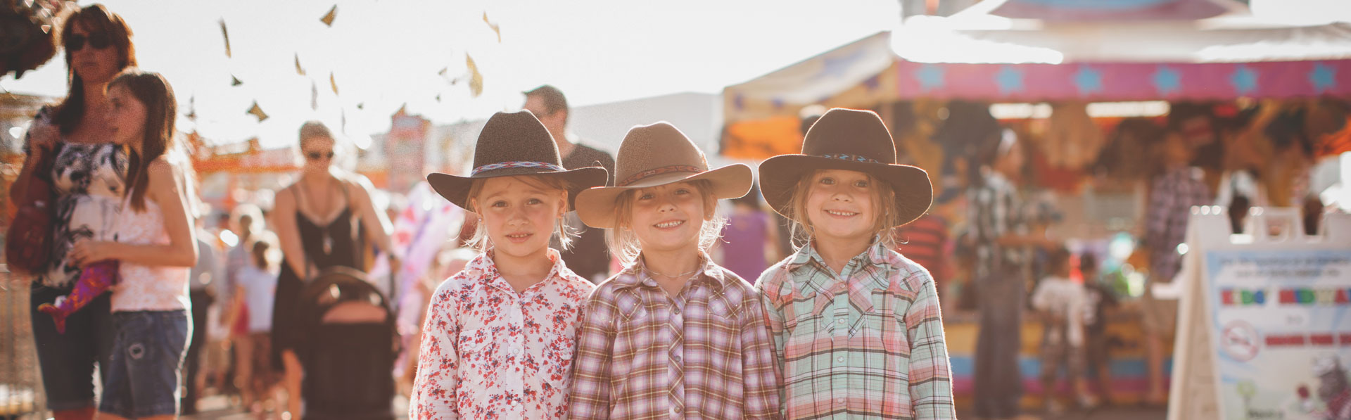 Three children in western wear posing in the Calgary Stampede Midway