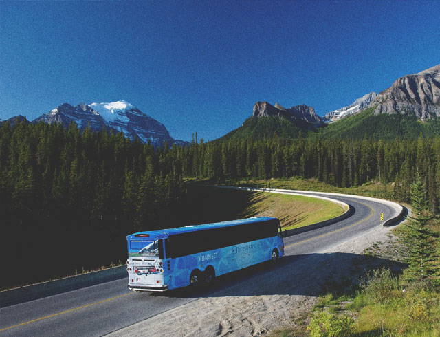 A bus driving through the mountains around Calgary taking people on a tour