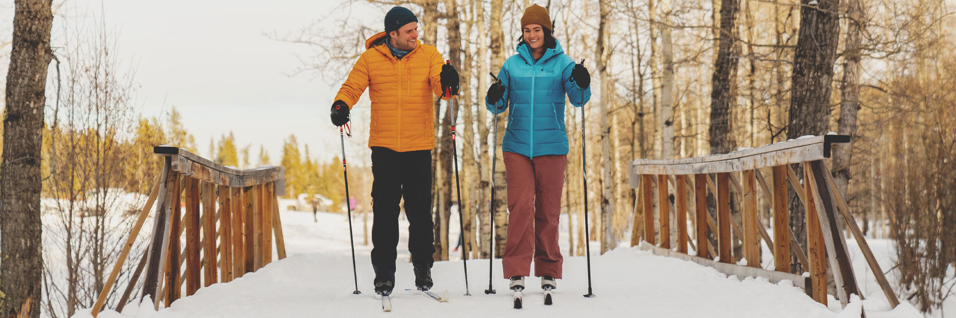 A couple cross-country skiing over a bridge in Calgary