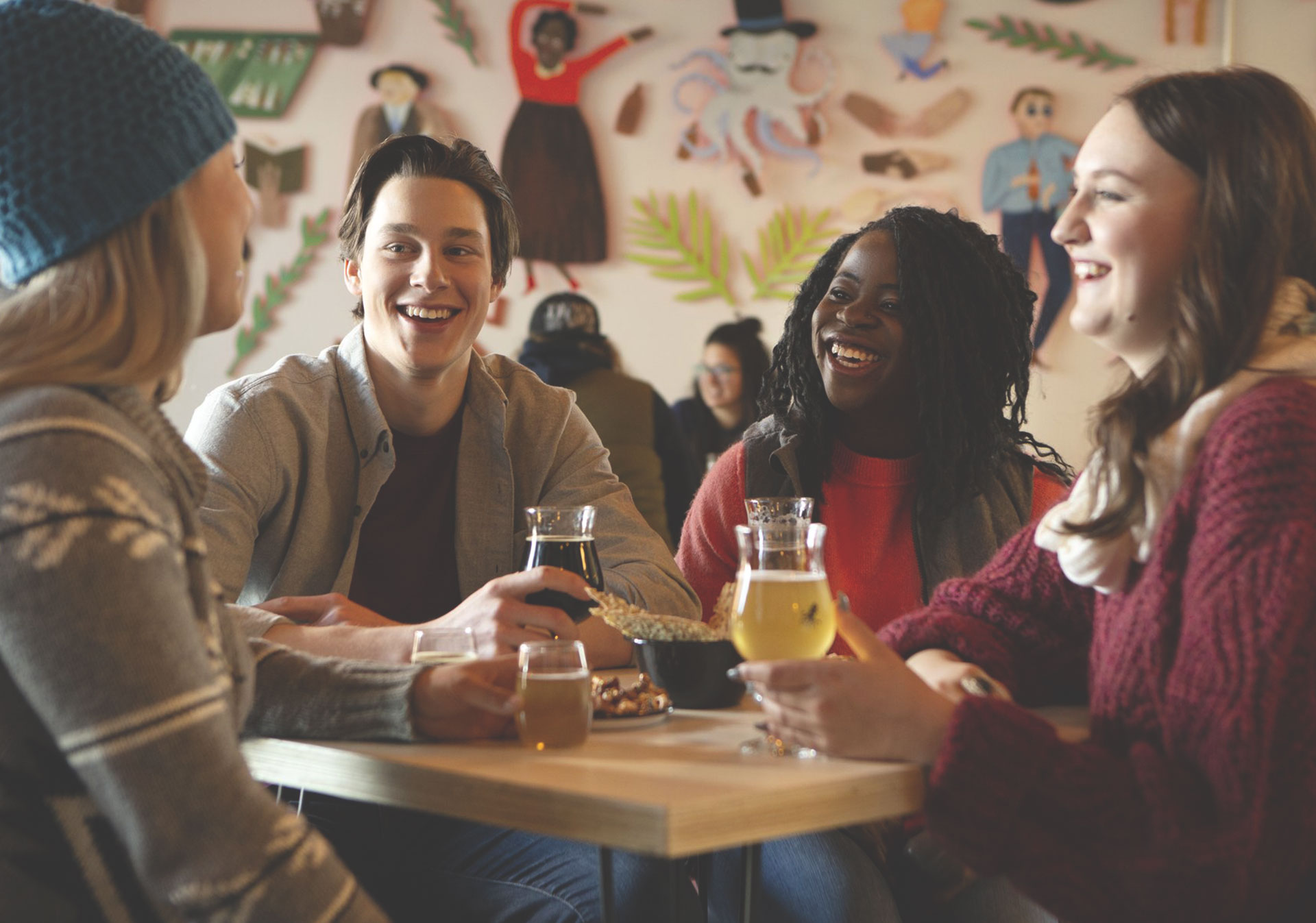 Friends laughing at a table together with beer
