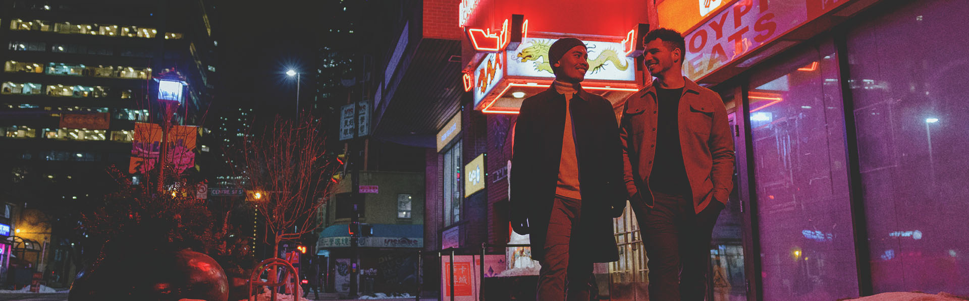 couple walking through Calgary's Chinatown at night with the illuminated Silver Dragon restaurant sign behind them