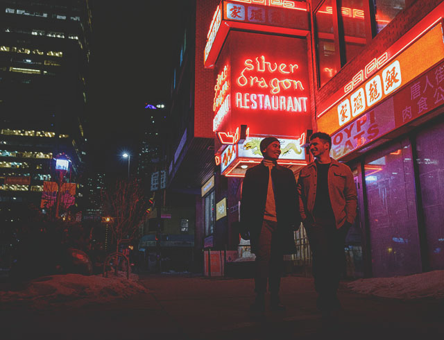 couple walking through Calgary's Chinatown at night with the illuminated Silver Dragon restaurant sign behind them