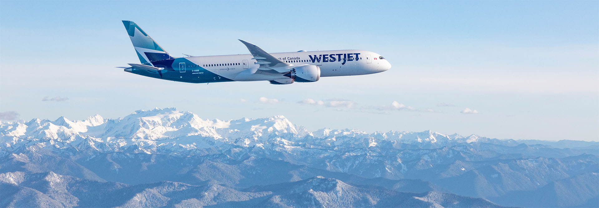 WestJet Aircraft flying over mountain range