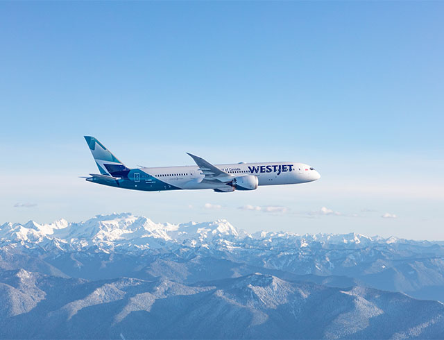 WestJet Aircraft flying over mountain range