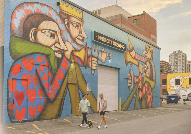 Couple walking their dog in front of a BUMP Mural in downtown Calgary