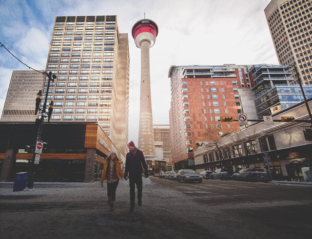 Couple walking along Stephen Avenue in winter with the Calgary Tower in the background