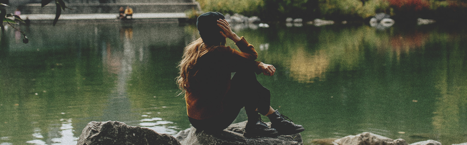 woman sitting on a rock at the edge of a pond in Prince's Island Park