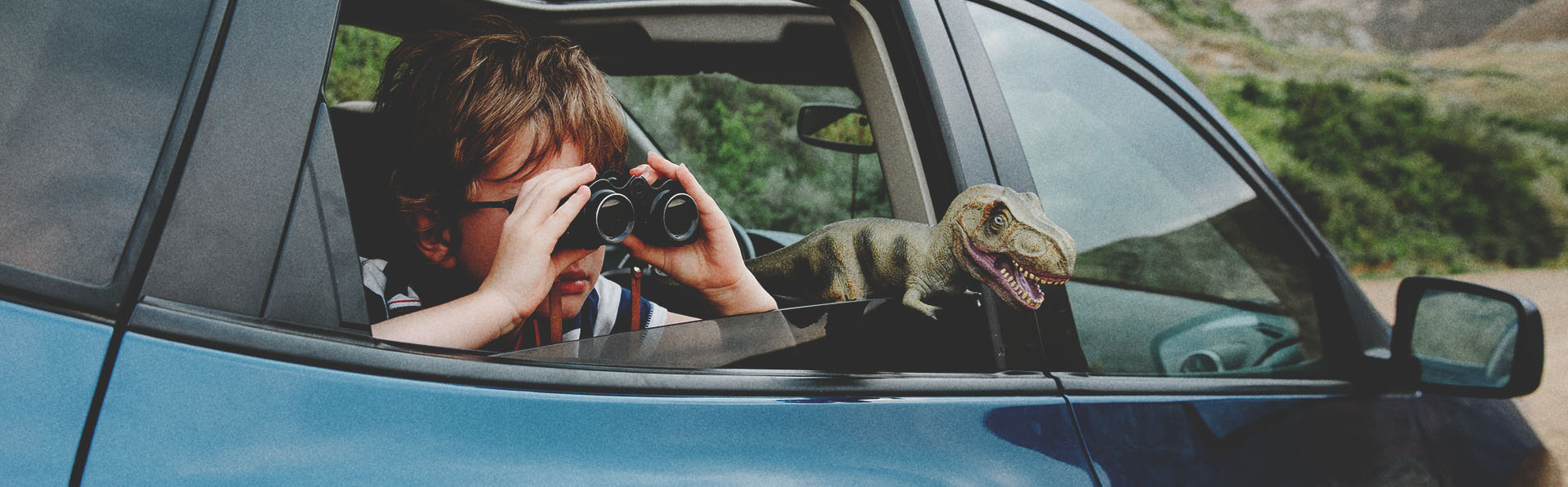 child looking through binoculars in the backseat of a vehicle