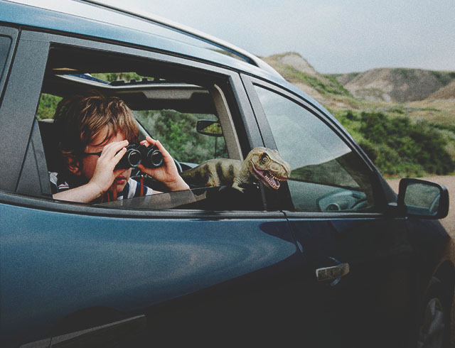 child looking through binoculars in the backseat of a vehicle