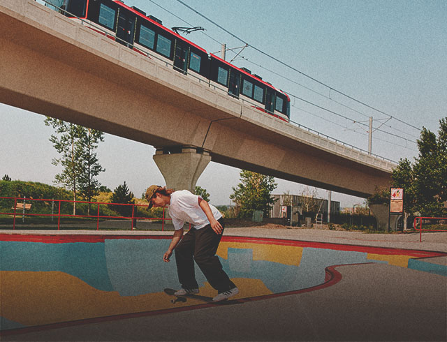 Person skateboarding at Shaw Millennium Park with the CTrain passing overhead