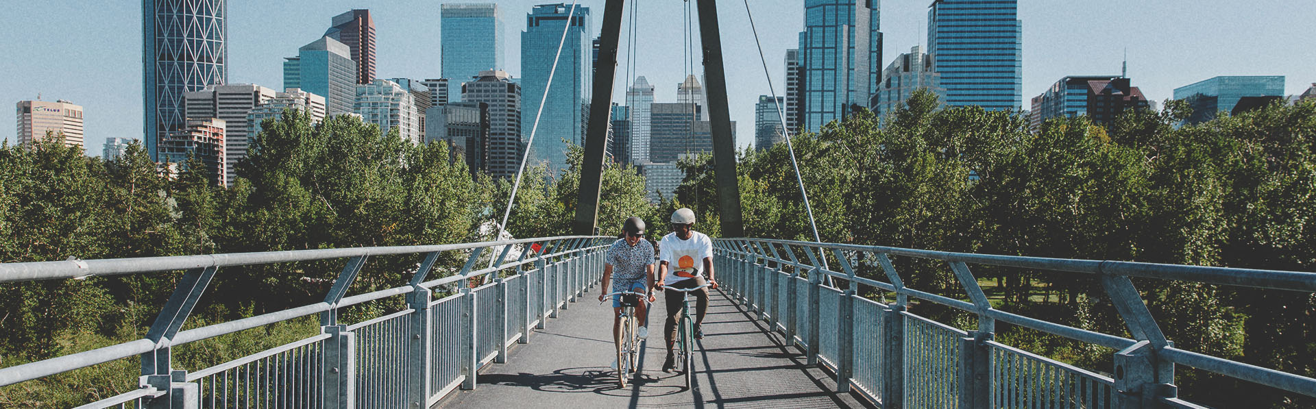 Friends biking over the Bow River pathway bridge