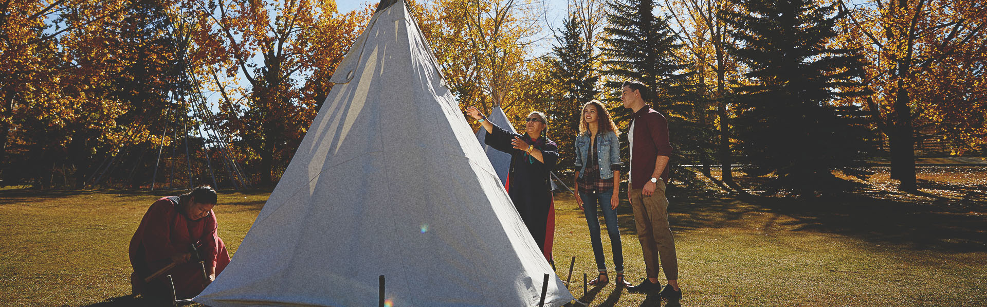 People learning how to set up a tipi at Heritage Park