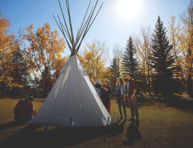 People learning how to set up a tipi at Heritage Park