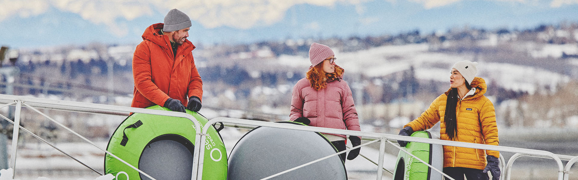 family at WinSport's Servus Tube Park with mountains in the background