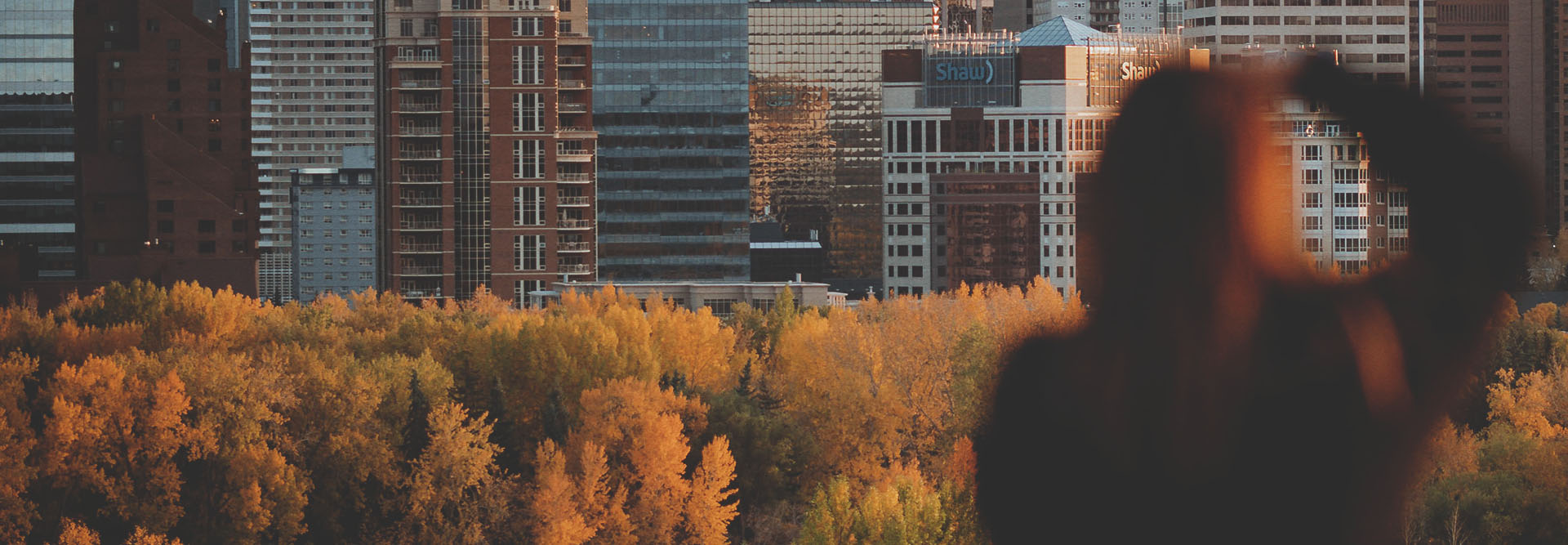 woman photographing the downtown Calgary skyline during autumn