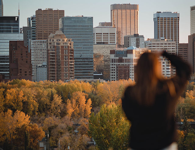 woman photographing the downtown Calgary skyline during autumn