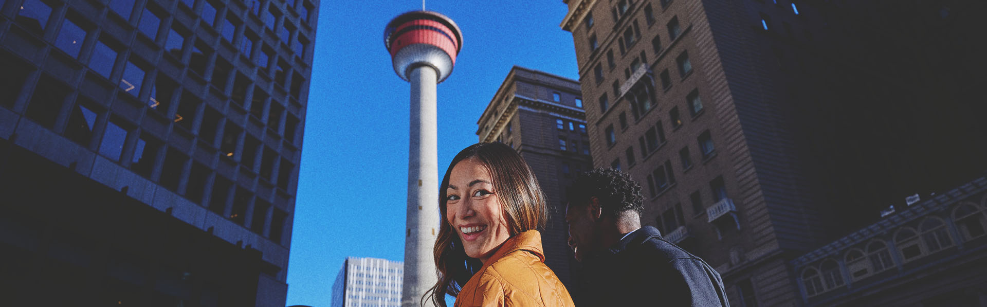 couple listening to a street busker play guitar in front the the Calgary Tower