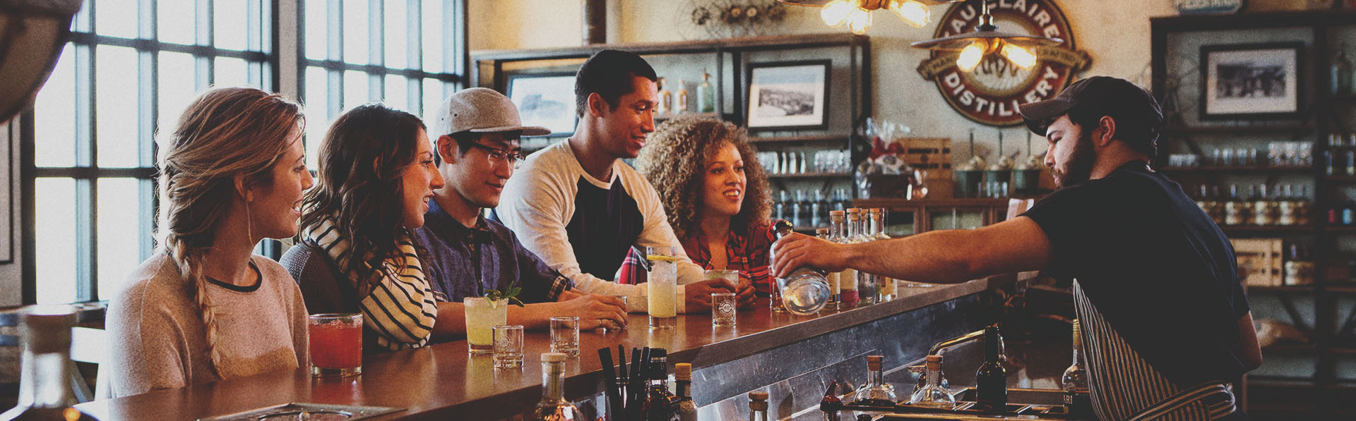 group of four at the bar of Eau Claire Distillery sampling farm to table spirits