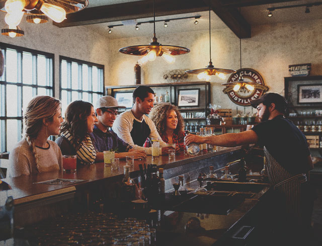 group of four at the bar of Eau Claire Distillery sampling farm to table spirits