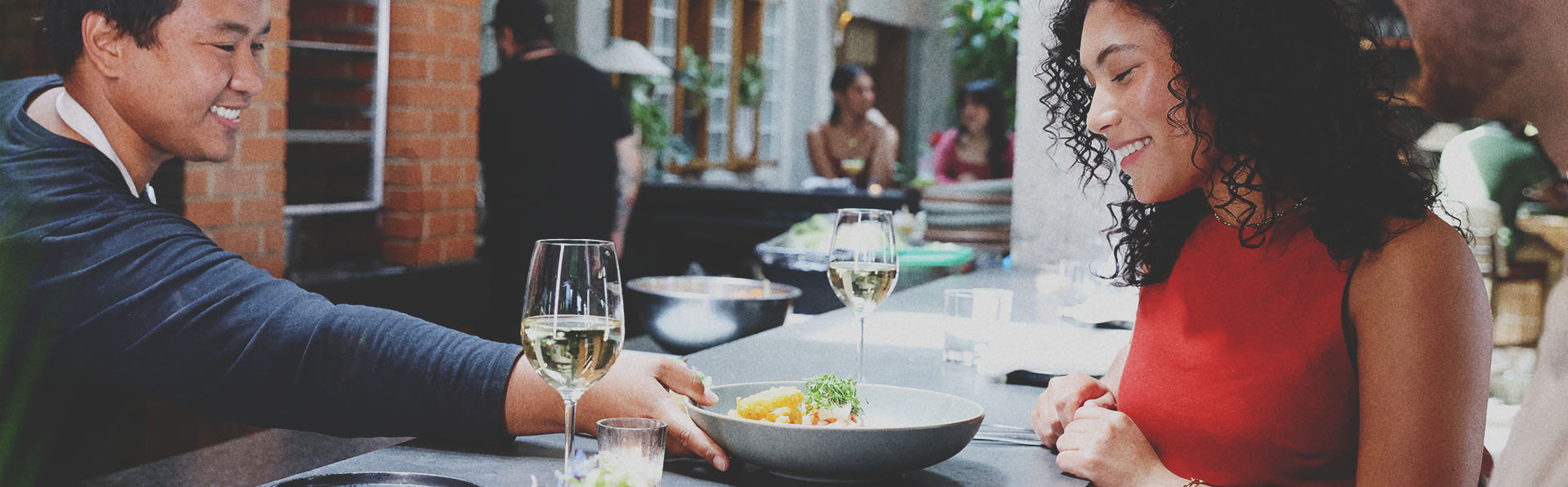 server setting down a dish in front of two patrons at the bar top at Fortunas Row