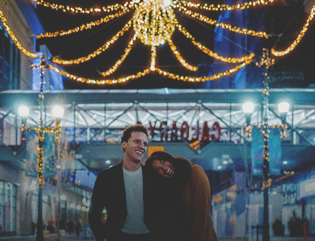 couple walking along Stephen Ave with outdoor lights strung behind them