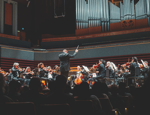 a full crowd of spectators enjoying a performance by the Calgary Philharmonic Orchestra