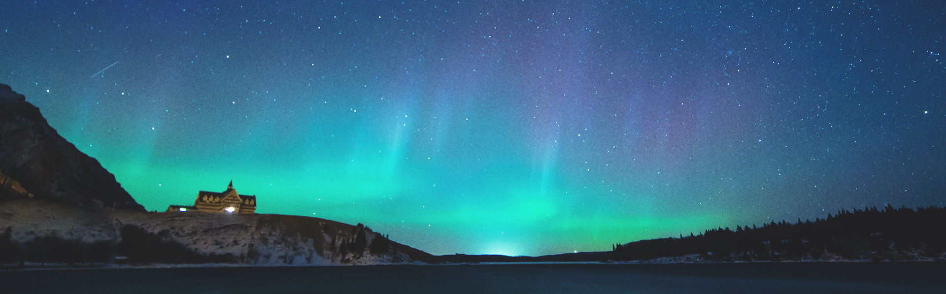 The Northern Lights shine brightly above Prince of Wales Hotel in Waterton Lakes National Park at night