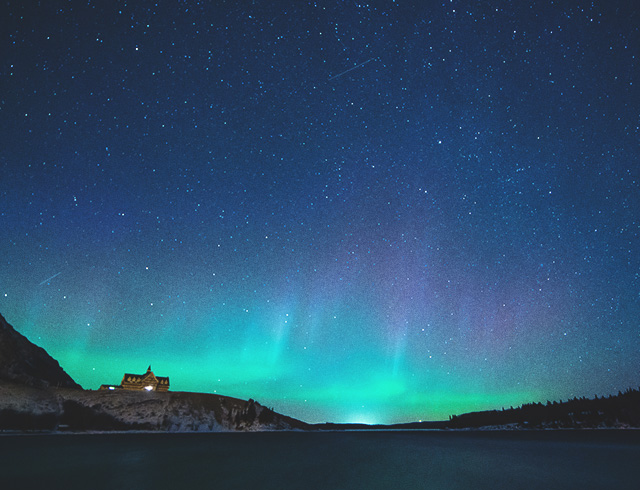 The Northern Lights shine brightly above Prince of Wales Hotel in Waterton Lakes National Park at night