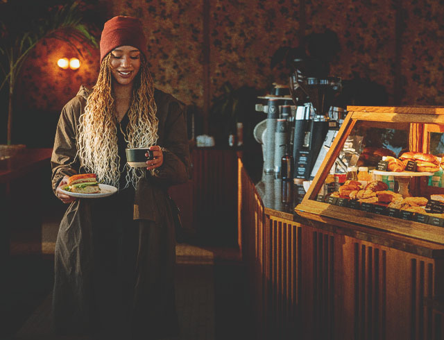 woman carrying a sandwich and latte in a local calgary coffee shop