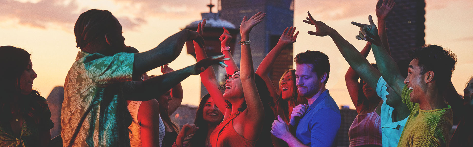 group of friends dancing on an outdoor rooftop with the Calgary skyline in the background