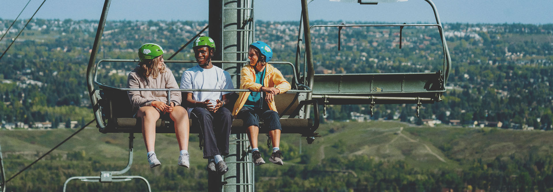friends riding the WinSport chairlift up to Downhill Karting