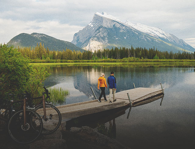 Couple walking on dock after riding bikes at Vermillion Lakes in Banff