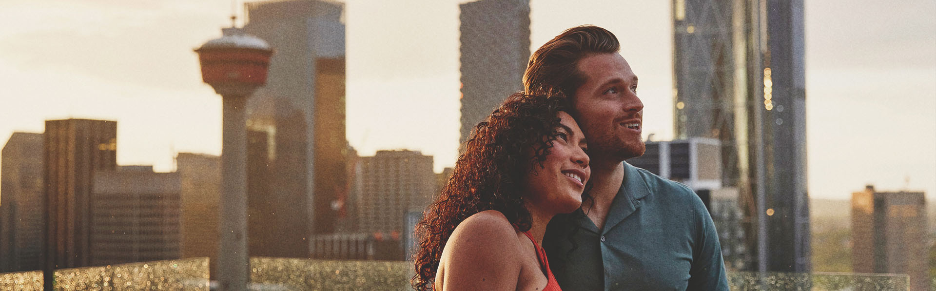 a man and a woman standing on a balcony with a city skyline