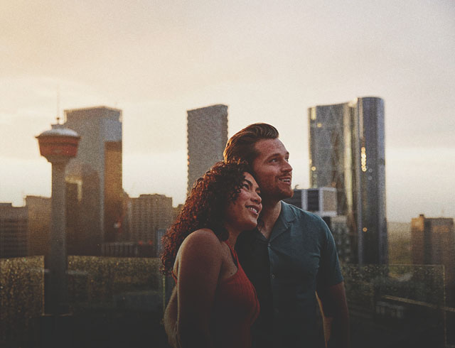 a man and a woman standing on a balcony with a city skyline
