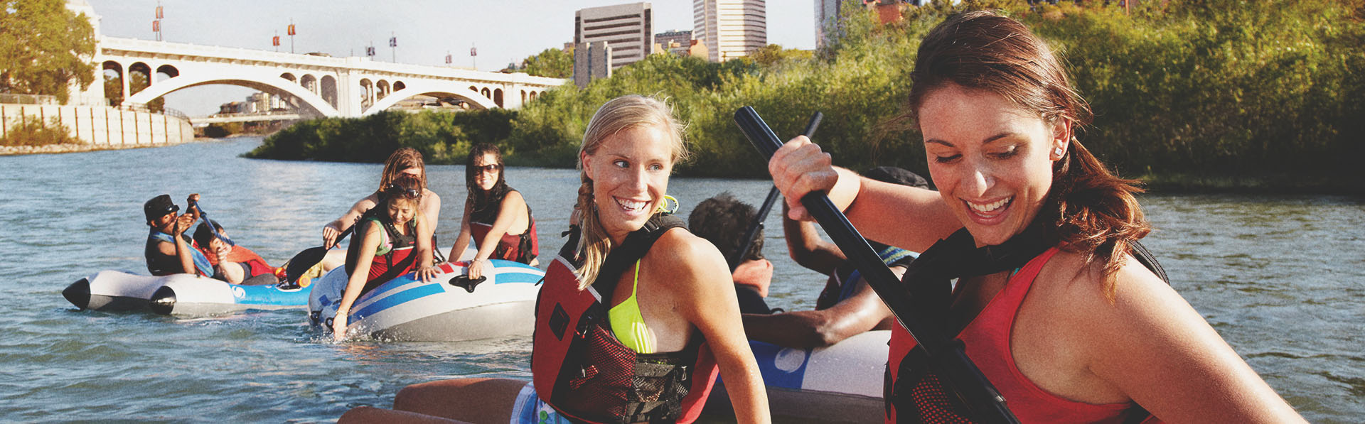 Group of young women rafting down the Bow River in Calgary with the city skyline in the background