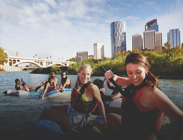 Group of young women rafting down the Bow River in Calgary with the city skyline in the background