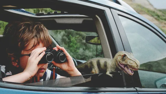 Kid looking outside through binoculars from a car.