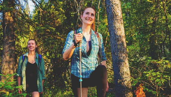 two women walking through the woods on a trail in Fish Creek Park