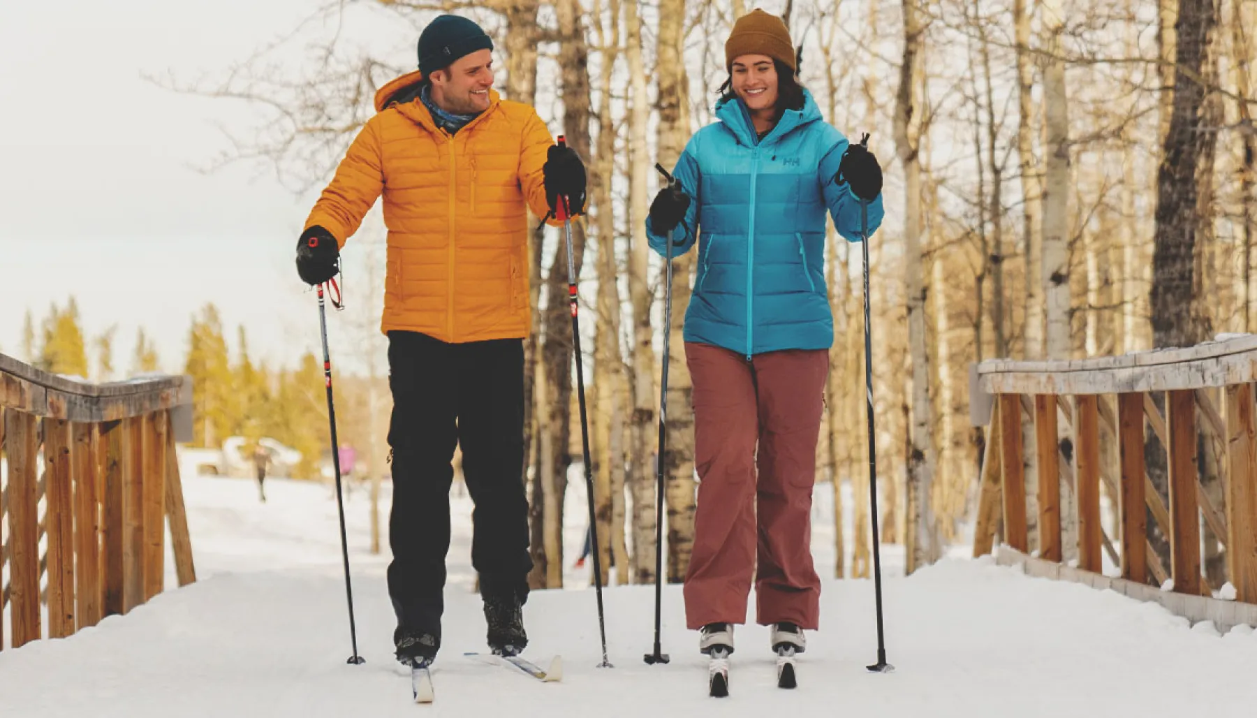 A couple cross-country skiing over a bridge in Calgary