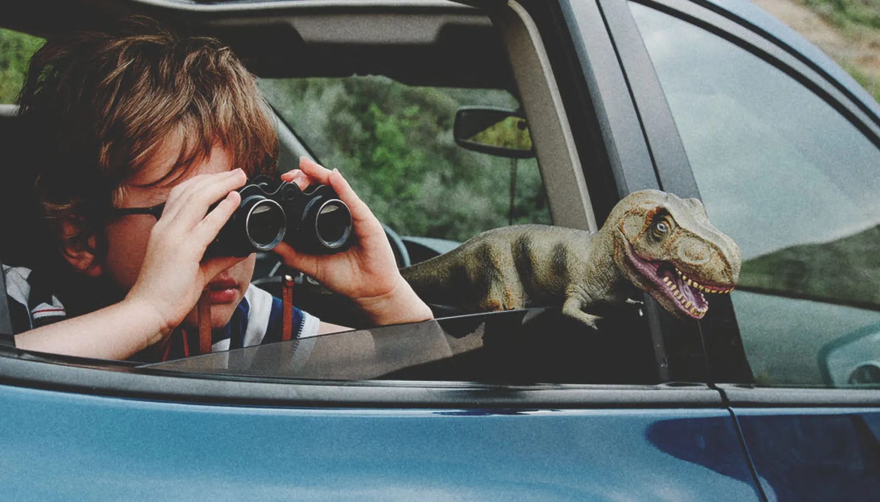 child looking through binoculars in the backseat of a vehicle