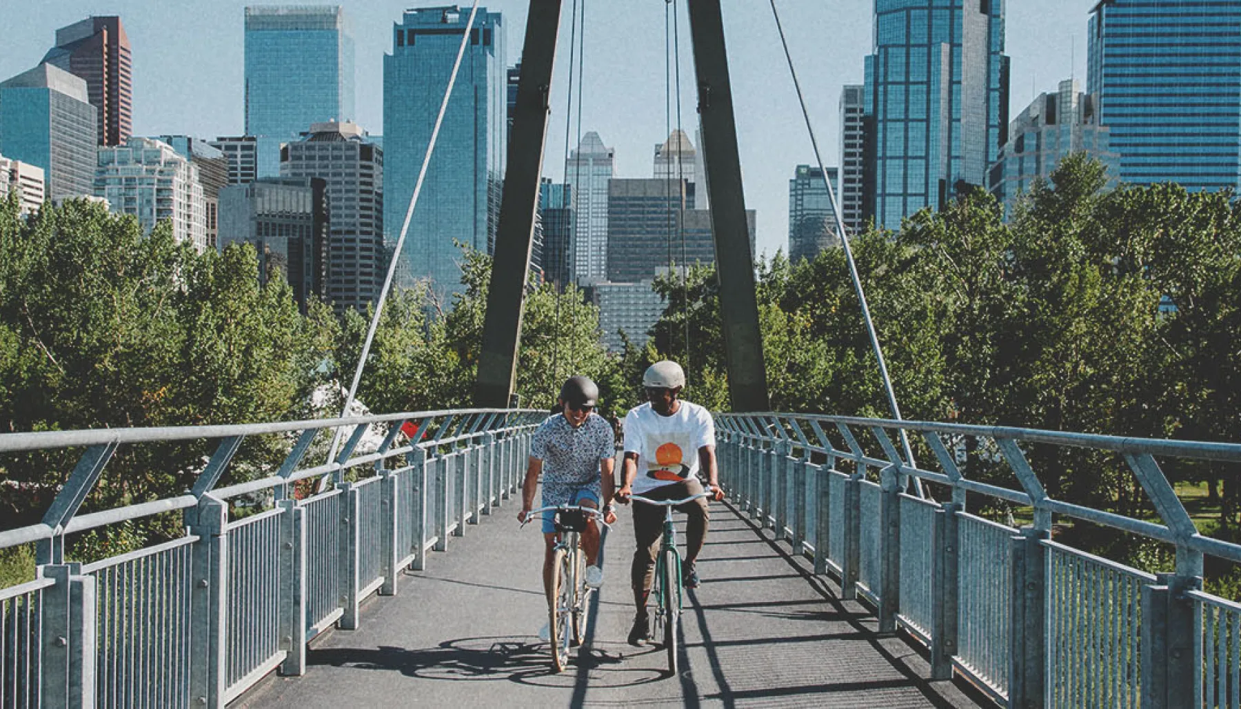 Friends biking over the Bow River pathway bridge