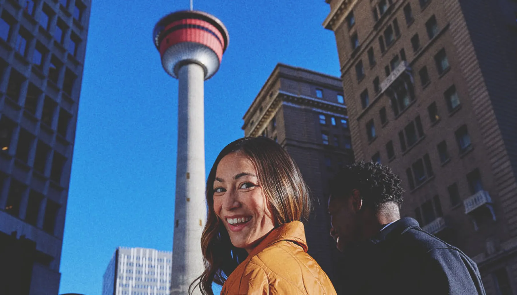 couple listening to a street busker play guitar in front the the Calgary Tower
