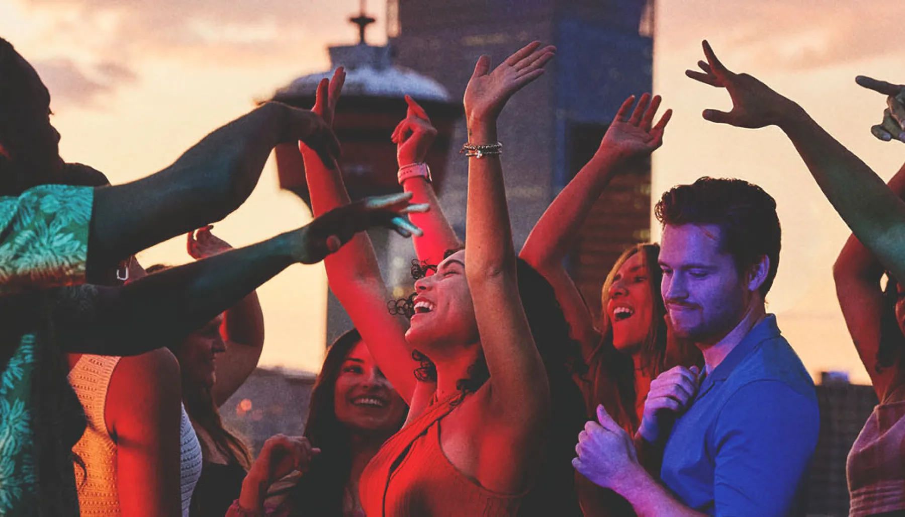 group of friends dancing on an outdoor rooftop with the Calgary skyline in the background