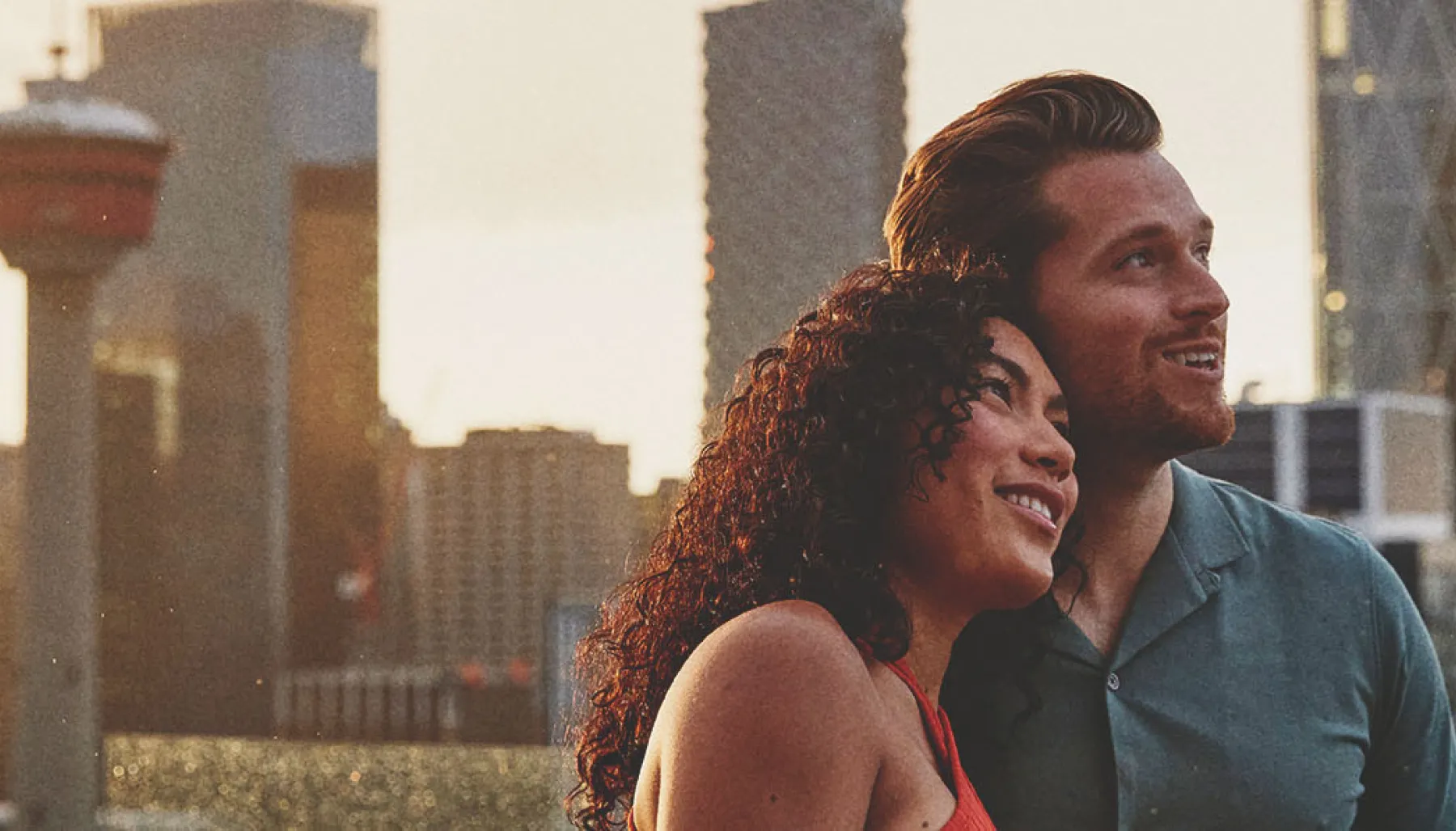 a man and a woman standing on a balcony with a city skyline