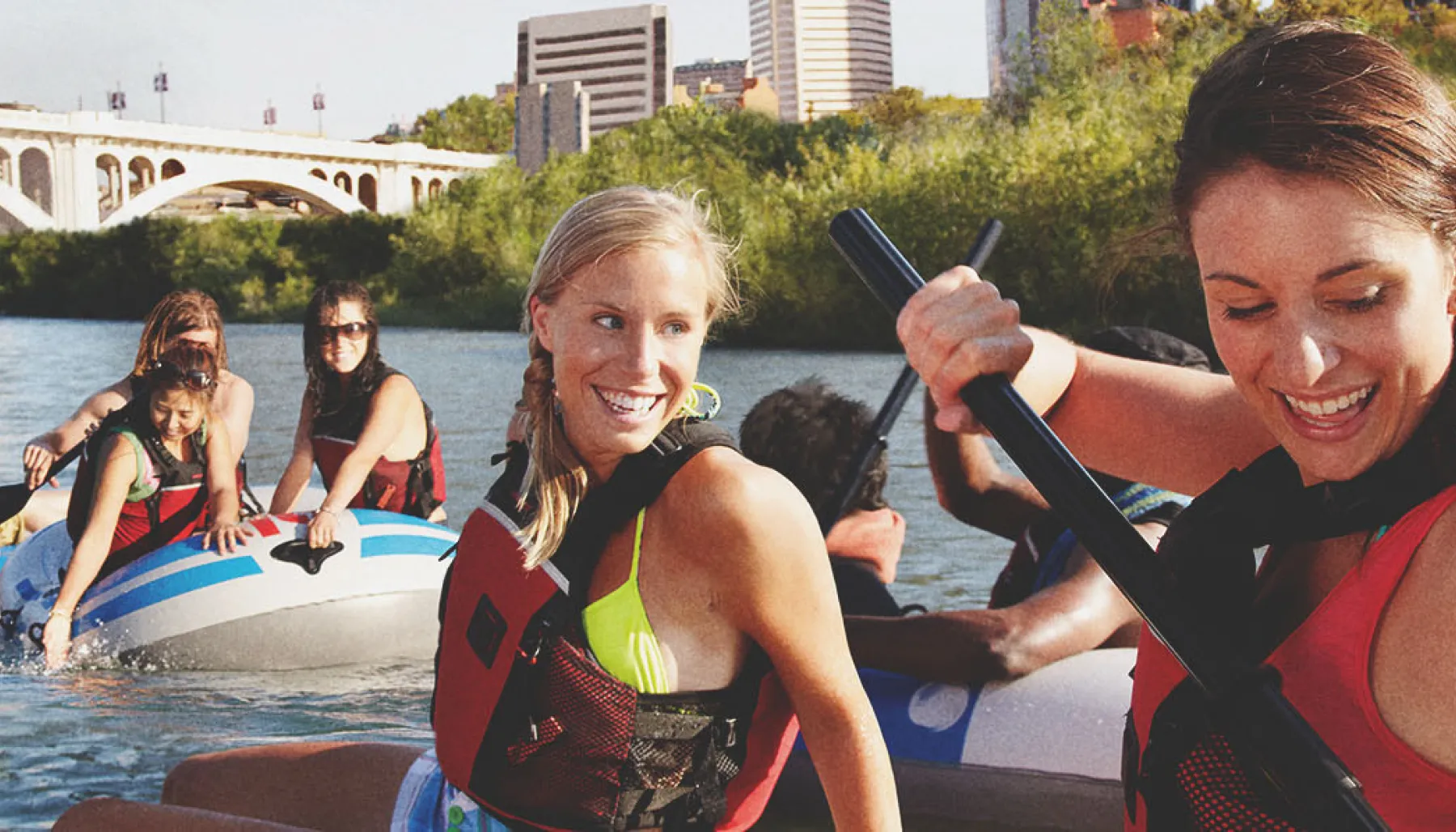 Group of young women rafting down the Bow River in Calgary with the city skyline in the background