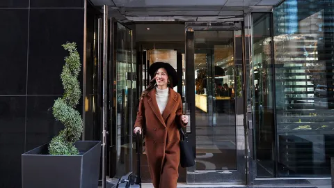 Woman walking out of a downtown Calgary hotel with her luggage