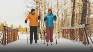 A couple cross-country skiing over a bridge in Calgary